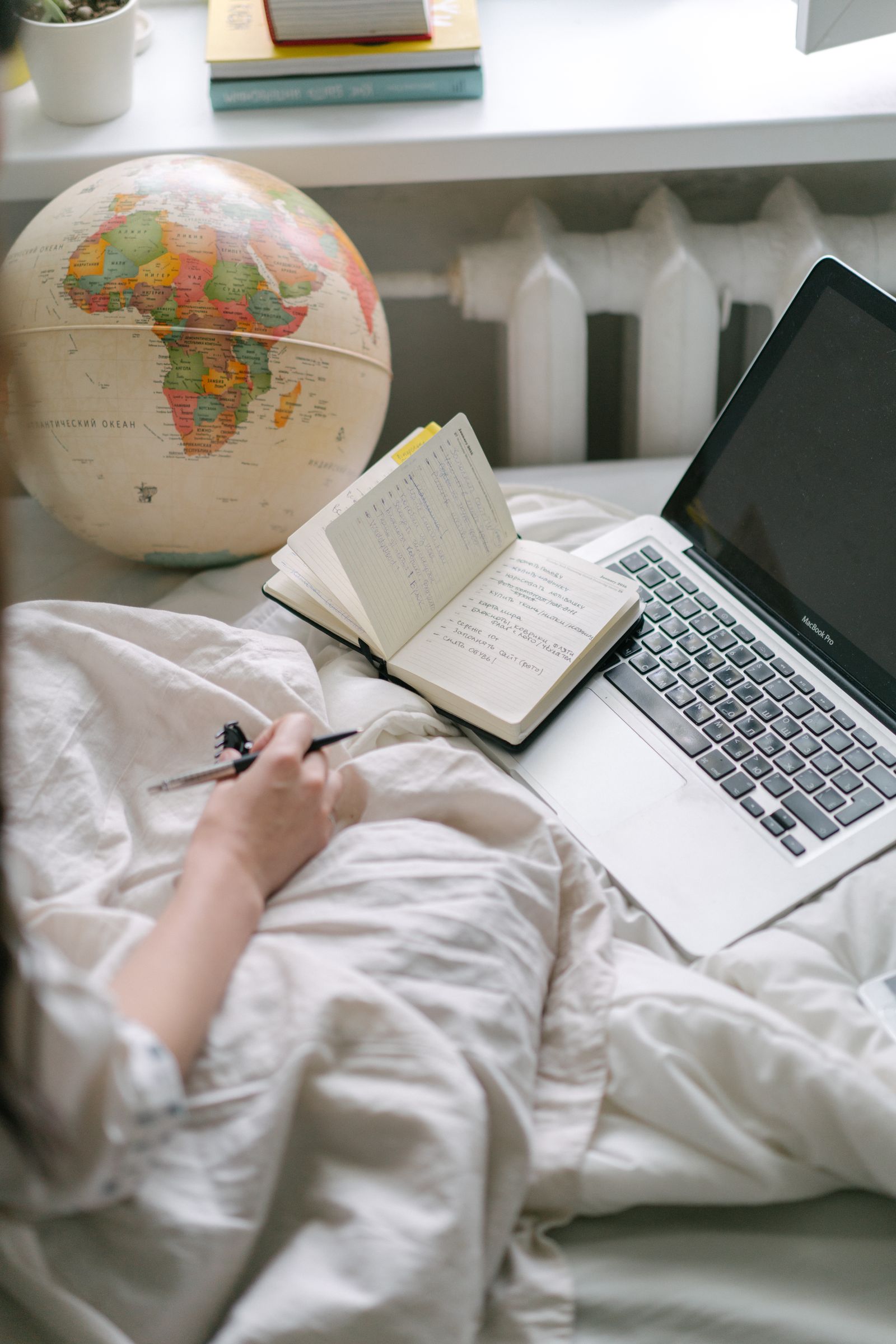 Globo terráqueo junto a una computadora y cuaderno de trabajo